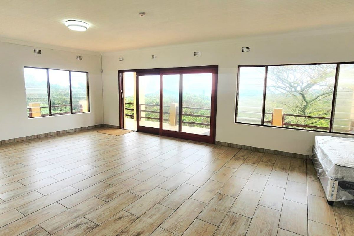 Spacious living area featuring large windows, tiled flooring, and sliding glass doors leading to an outdoor space.