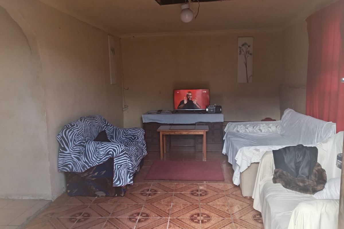 A living room area featuring ceramic floor tiles, currently requiring significant ceiling repairs and wall finishing to improve the overall condition.