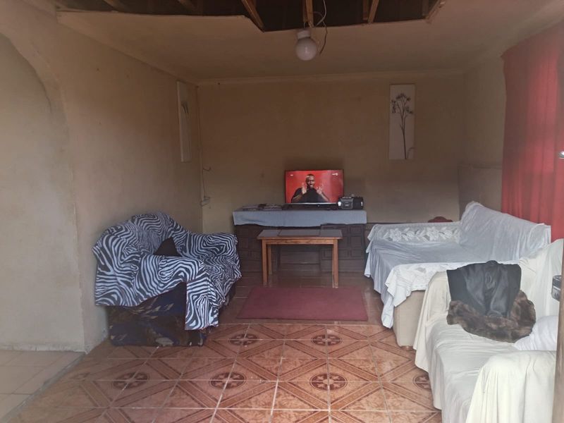 A living room area featuring ceramic floor tiles, currently requiring significant ceiling repairs and wall finishing to improve the overall condition.