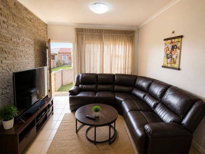 A comfortable living room featuring a textured stone accent wall, tiled flooring, and direct access to the rear garden area.