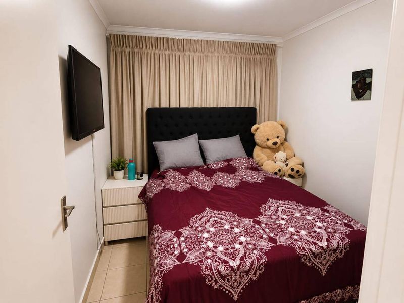 A compact bedroom featuring tiled flooring and neutral curtains, providing a functional and cozy sleeping space.