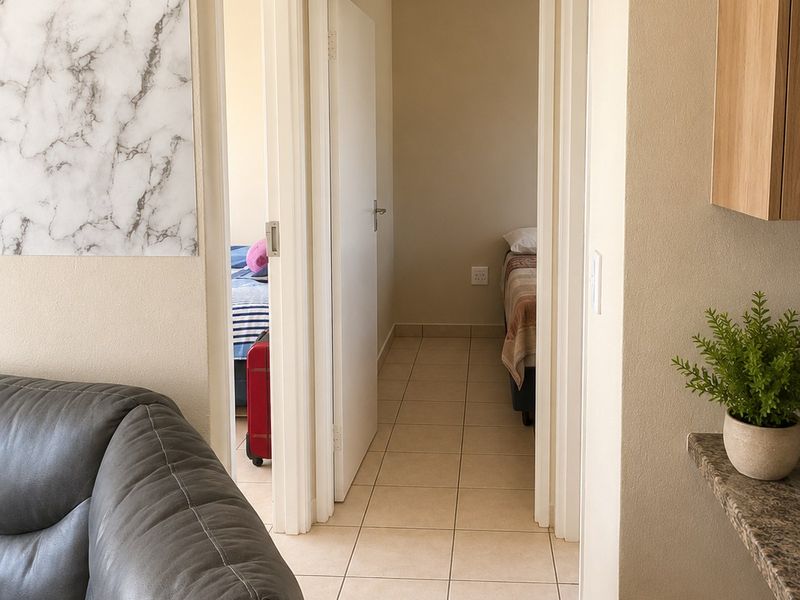 A functional hallway with neutral tiled flooring connecting the living area to the bedrooms.