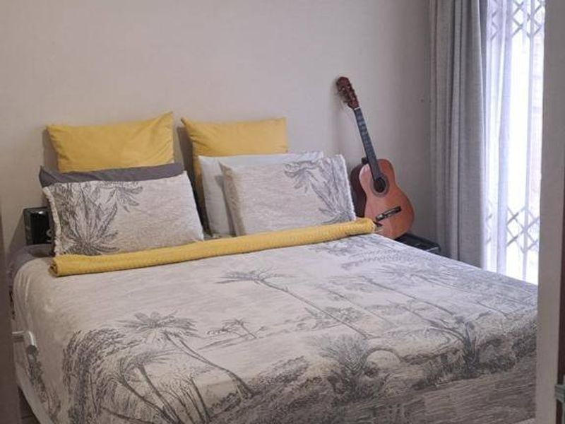 A functional bedroom featuring tiled flooring and a sliding glass door with security gate, providing access to the exterior.