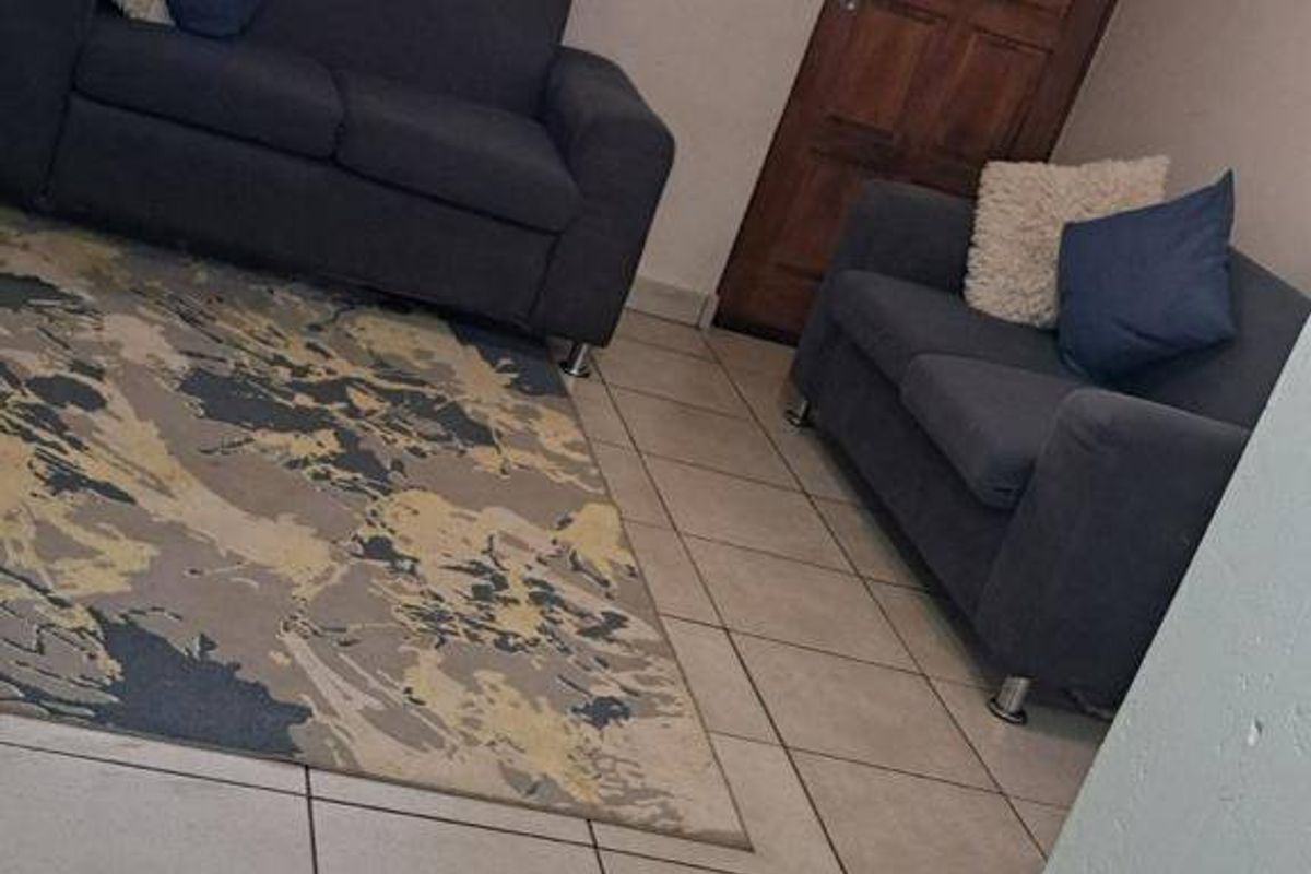 A living room area featuring tiled flooring, a timber door, and a window, providing a functional space for relaxation.