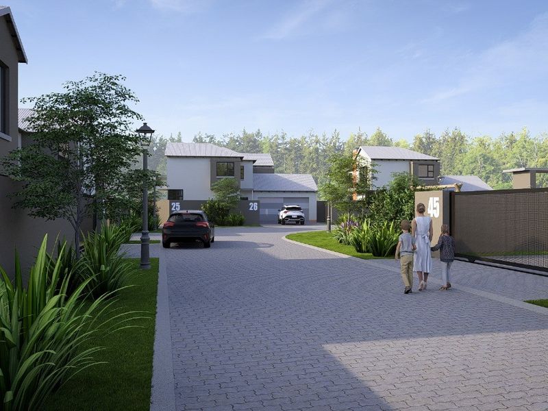 A view of a modern residential estate street featuring paved driveways, boundary walls, and contemporary house facades.