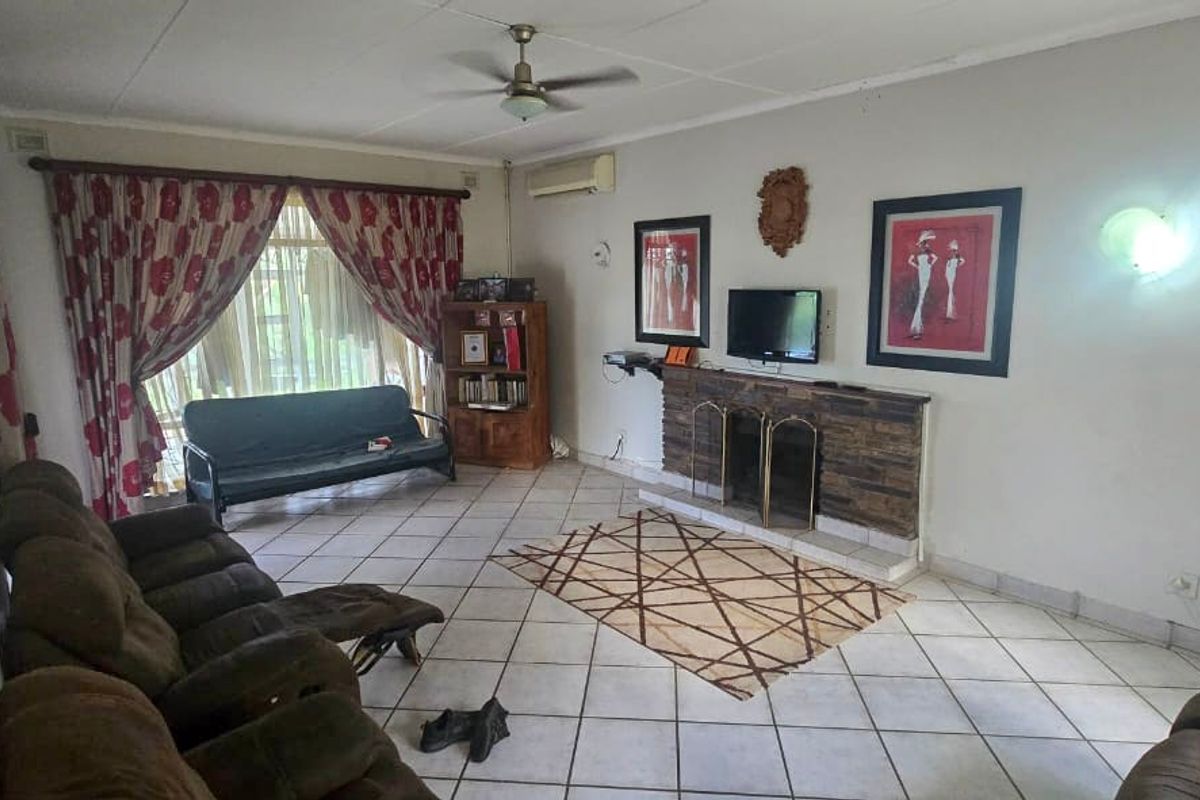 Spacious living room featuring a brick fireplace, ceiling fan, and split-system air conditioning, finished with tiled flooring throughout.