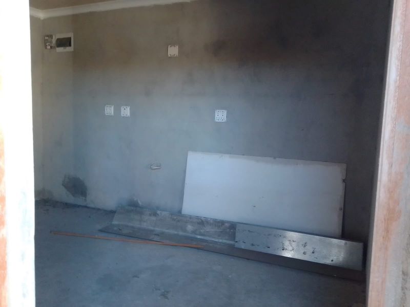An unfinished utility space featuring exposed concrete walls and flooring, with visible electrical points and plumbing connections, requiring completion and finishing.
