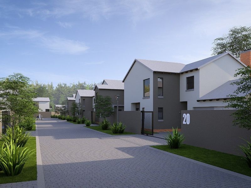 A street view of a modern residential complex featuring paved driveways, landscaped gardens, and contemporary house facades.