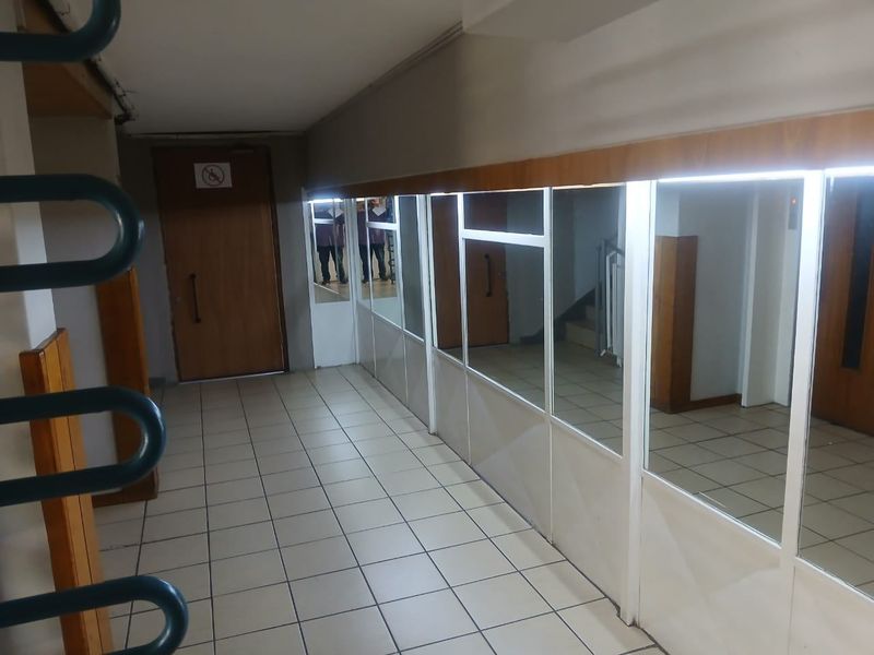 A functional apartment hallway featuring tiled flooring, mirrored wall panels, and integrated LED lighting.