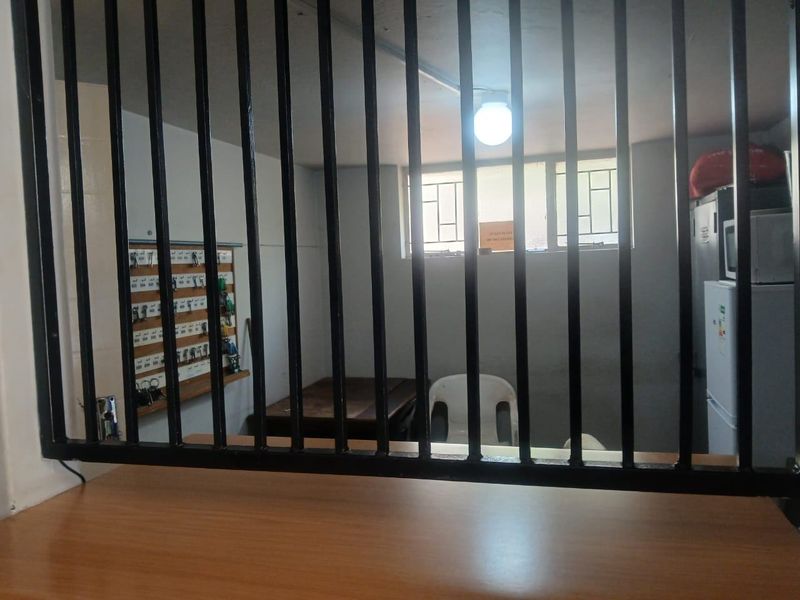 A utility or security office space featuring a service counter with heavy security bars and a wall-mounted key management system.