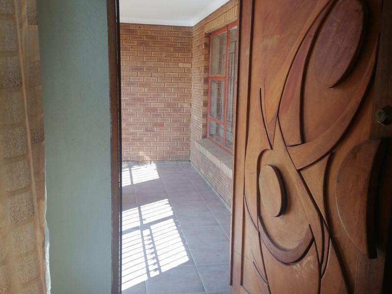 Entrance area featuring a decorative carved wooden door, tiled flooring, and exposed brick wall detailing.