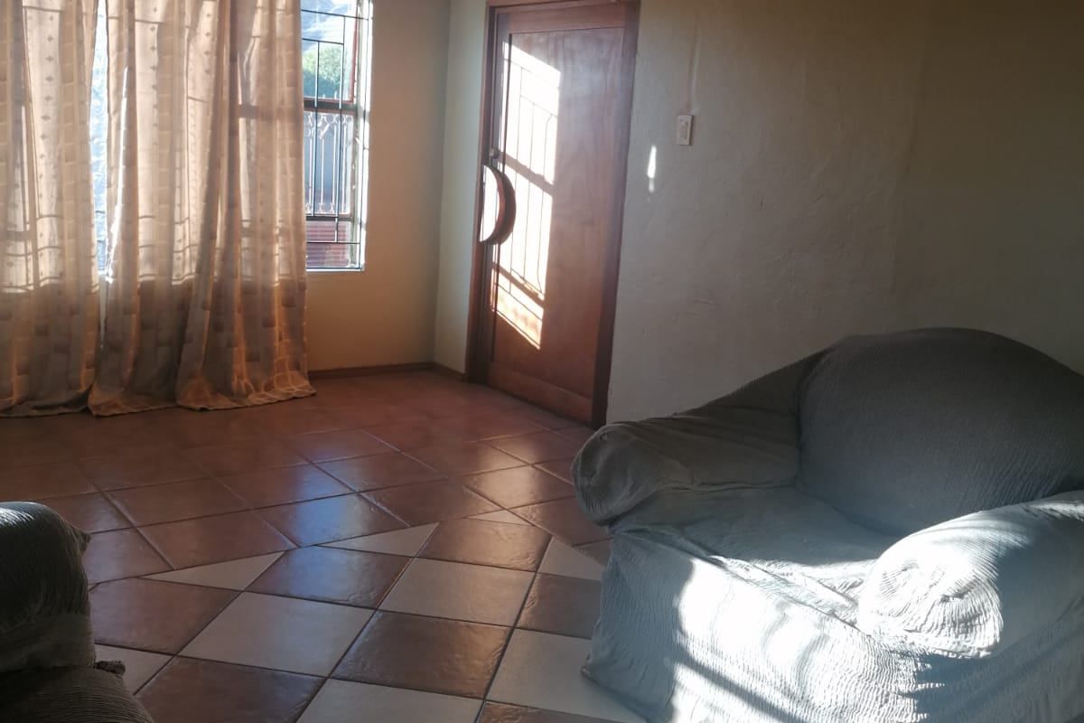 A living room featuring tiled flooring, recessed ceiling lighting, and a timber door with an integrated security gate.
