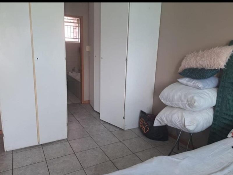 Bedroom featuring tiled flooring and built-in cupboards, with an adjoining bathroom visible through the doorway.