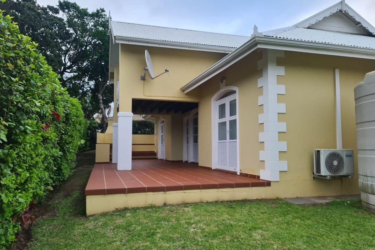 A view of the rear exterior of the house, featuring a covered patio with tiled flooring, white trim detailing, and a well-maintained garden area.