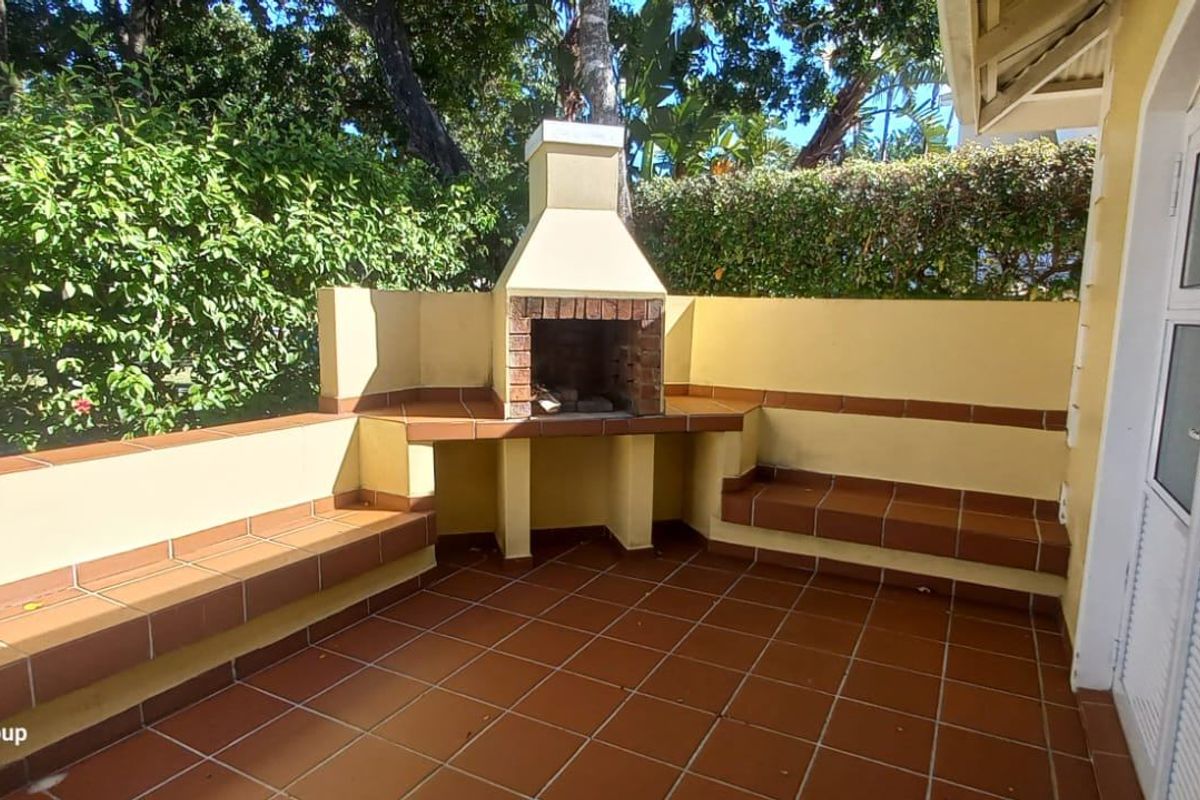 Outdoor patio area featuring a built-in brick braai fireplace, tiled flooring, and integrated bench seating, perfect for alfresco dining and entertaining.