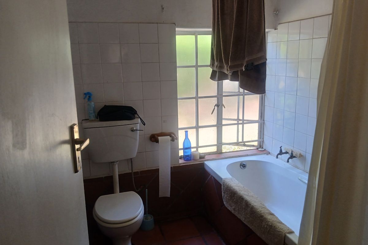 A dated bathroom featuring a built-in bathtub, toilet, and tiled finishes, requiring modernization to improve its overall aesthetic and functionality.