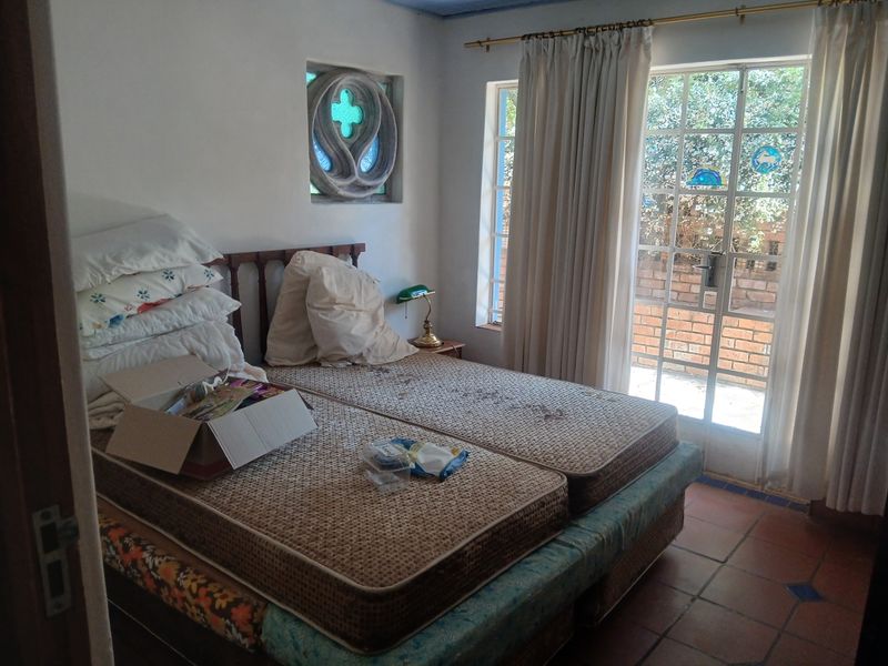A bedroom featuring terracotta floor tiles, a unique decorative stone window, and direct access to an outdoor patio area through a glass door.