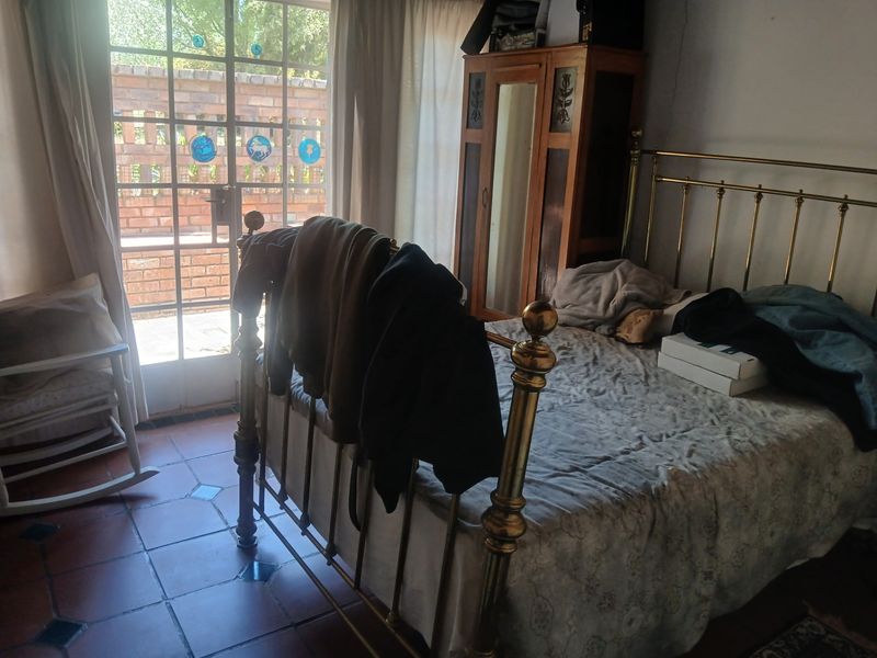 A bedroom featuring terracotta floor tiles and a glass panel door providing direct access to the exterior.
