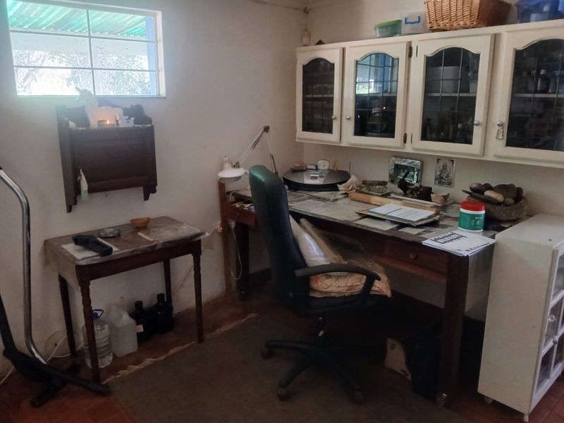 A functional home office space featuring built-in wall-mounted cabinetry and a window with security bars, offering a practical workspace area.