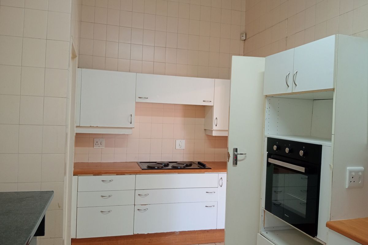 A functional kitchen featuring white built-in cabinetry, a fitted electric hob, and a built-in oven with tiled wall finishes.