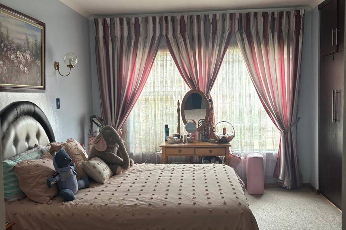 A bedroom featuring carpeted flooring, a built-in wardrobe, and a wall-mounted light fixture, providing a functional and comfortable living space.
