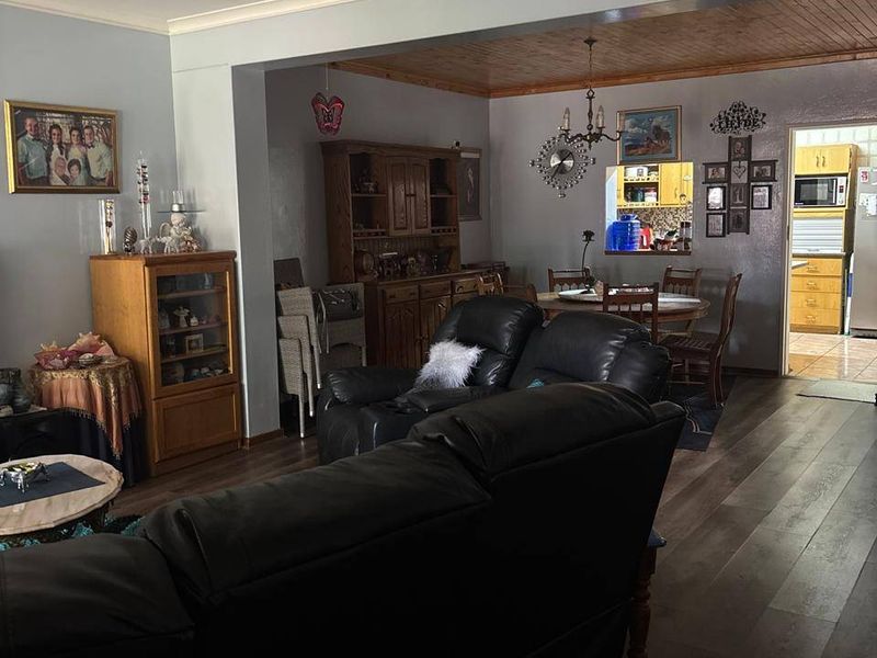 Open plan living and dining area featuring laminate flooring, timber ceiling accents, and a convenient pass-through window connecting to the kitchen.
