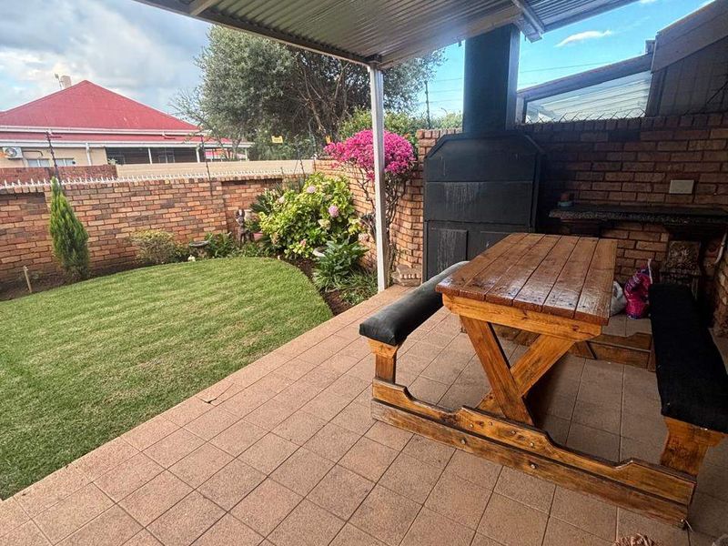 Covered patio area featuring a built-in braai, tiled flooring, and direct access to a private garden with brick boundary walls.