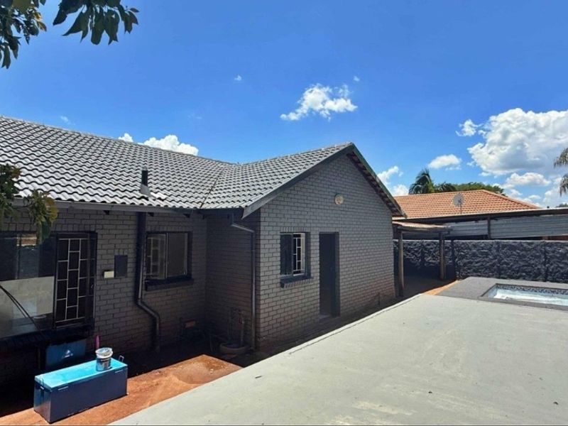 Rear view of the property featuring a brick facade, tiled roof, and a swimming pool area with a concrete patio.