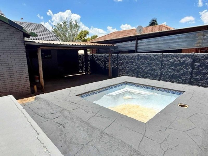 Outdoor pool area featuring a small swimming pool with a paved surround and an adjacent covered patio space.