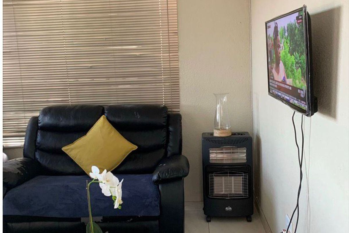 A living room area featuring tiled flooring and venetian blinds, providing a functional and neutral space.