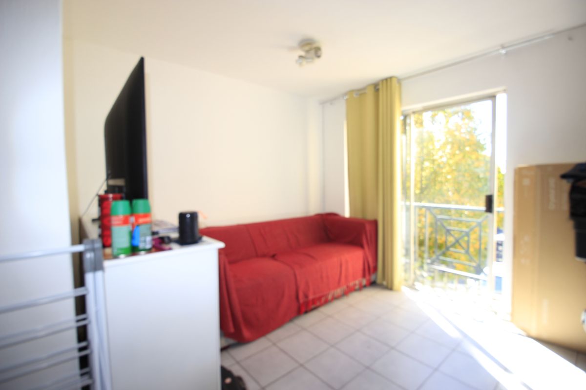A living room area featuring tiled flooring and a sliding glass door providing access to a balcony.