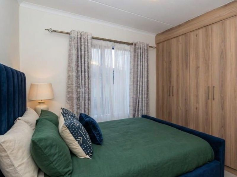 A well-maintained bedroom featuring light wood-finish built-in wardrobes and neutral wall finishes.