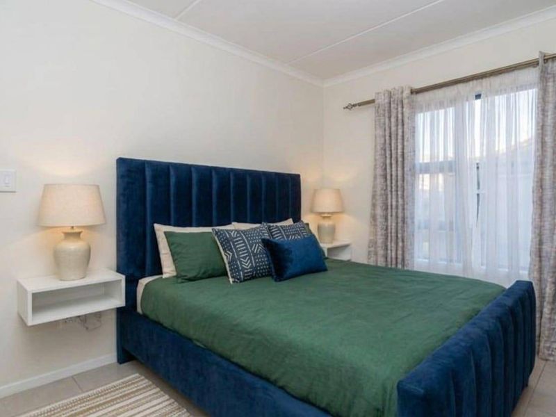 A well-maintained bedroom featuring neutral walls, tiled flooring, and floating bedside shelves, offering a clean and comfortable living space.