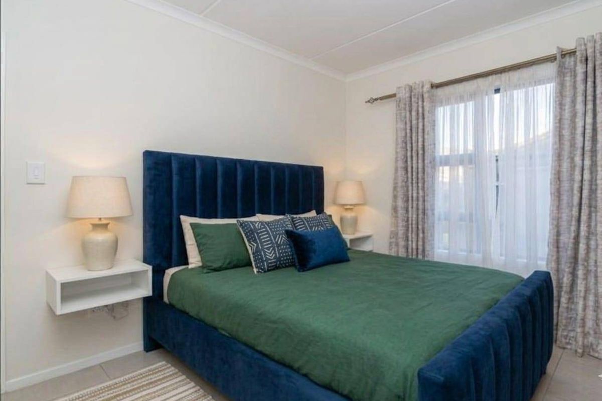 A well-maintained bedroom featuring neutral walls, tiled flooring, and floating bedside shelves, offering a clean and comfortable living space.