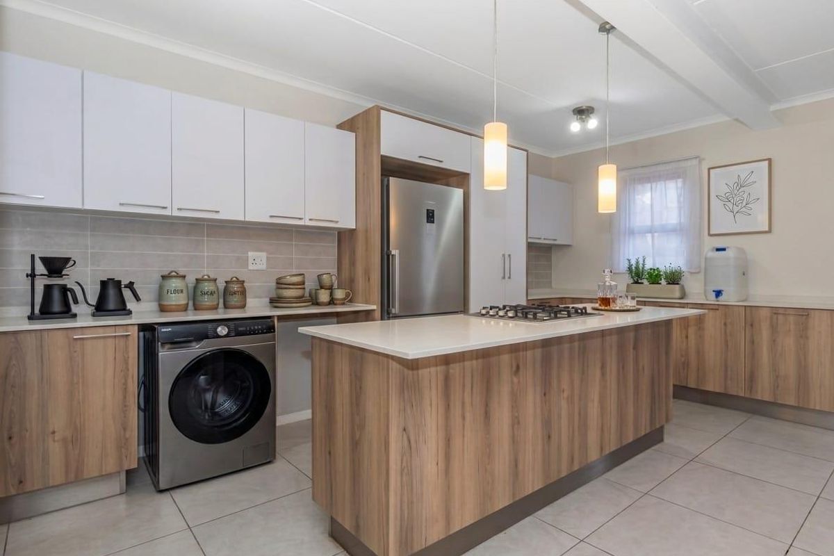 Modern kitchen featuring wood-grain and white cabinetry, stone countertops, a central island with a gas hob, and tiled flooring.