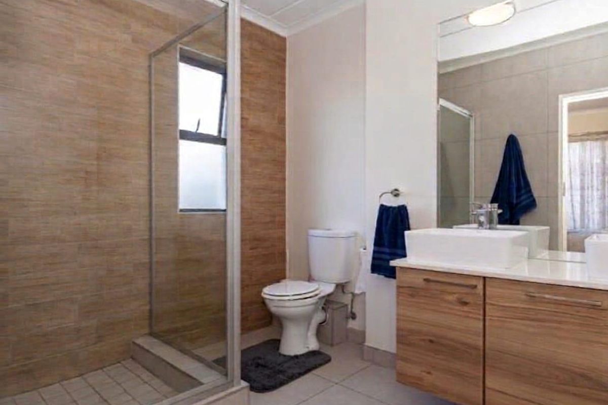 Modern bathroom featuring a glass-enclosed shower with wood-look tiling, a contemporary vanity with a vessel sink, and a large wall mirror.