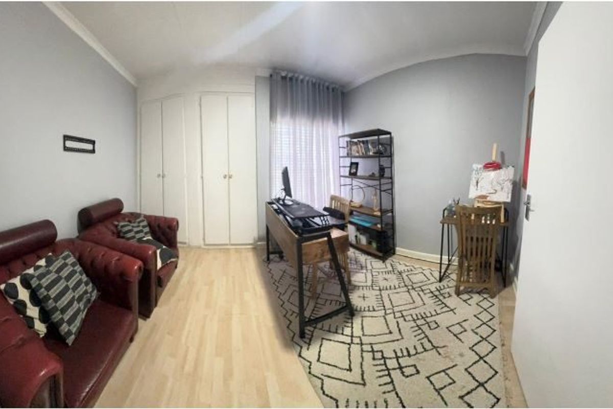 A bedroom featuring laminate flooring and built-in cupboards, currently utilized as a home office and creative space.