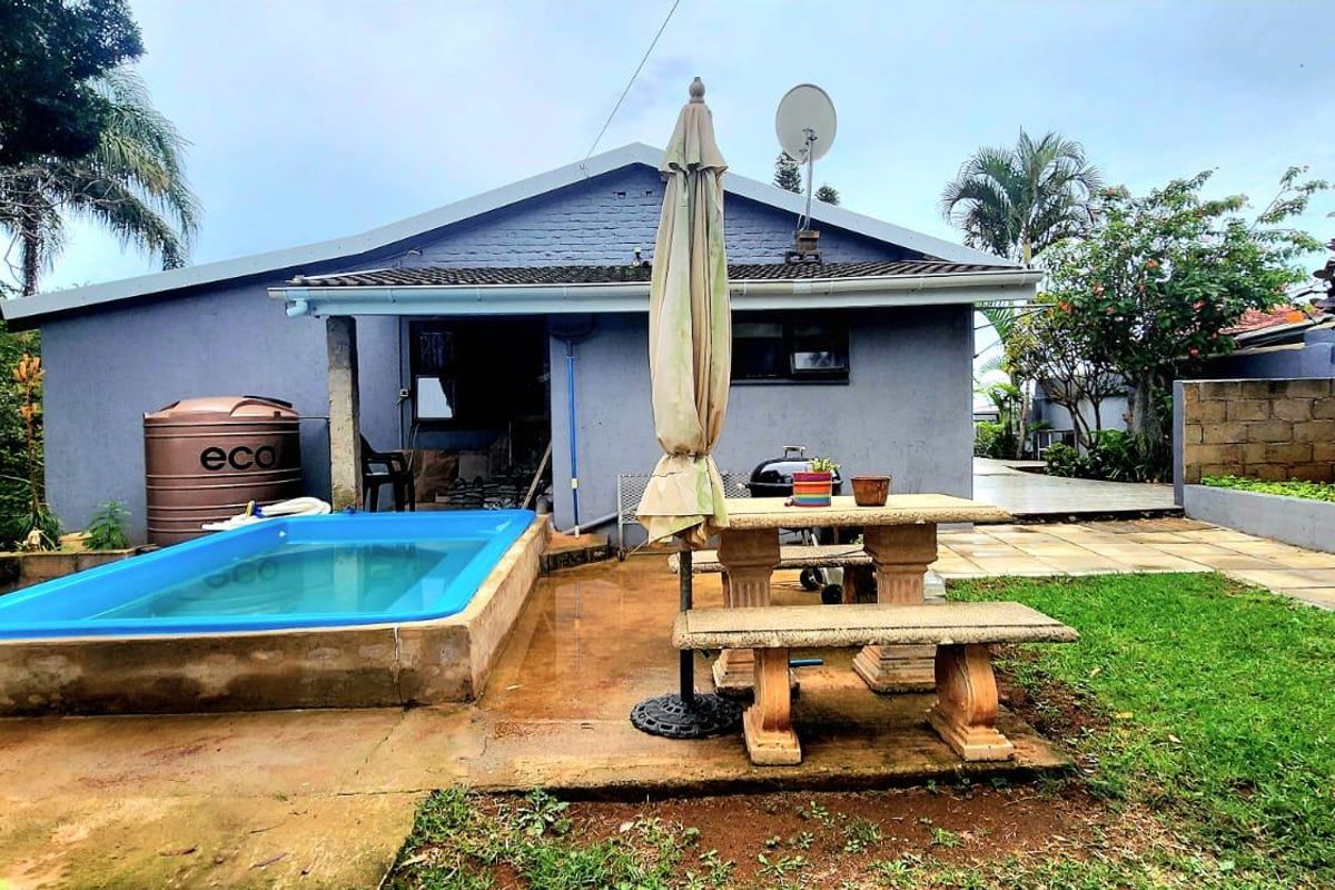 Rear exterior view featuring a small swimming pool, paved patio area, and a water storage tank set within a garden space.