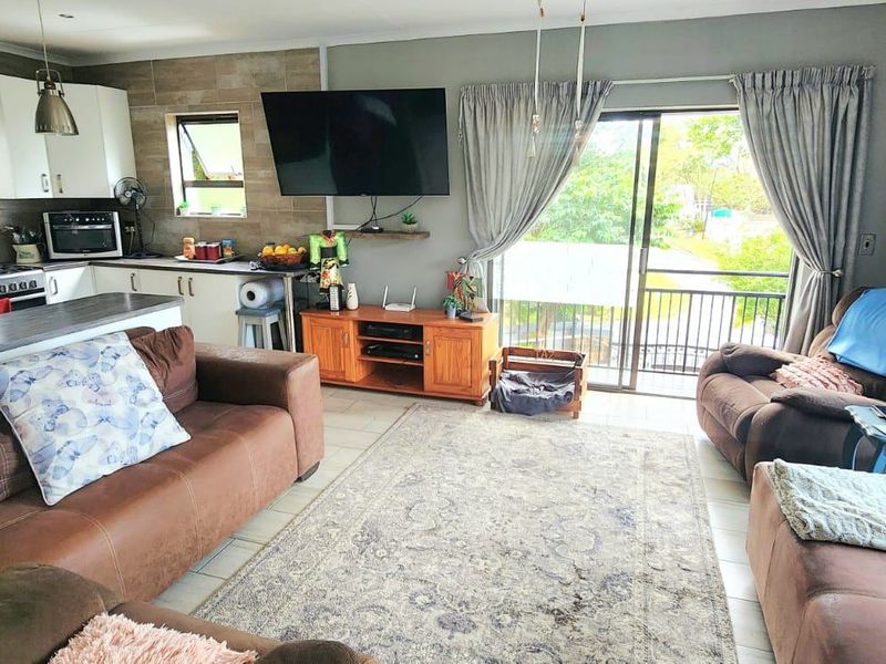 Open-plan living area featuring a modern kitchen with tiled splashbacks, gas hob, and direct access to an outdoor balcony through sliding glass doors.