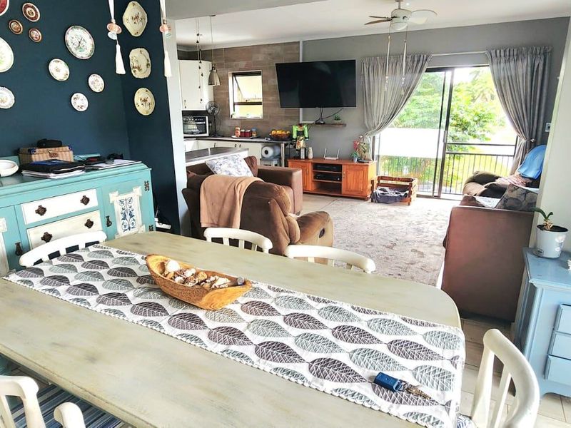 Open-plan living and dining area featuring tiled flooring, a ceiling fan, and direct access to an outdoor balcony through sliding glass doors.