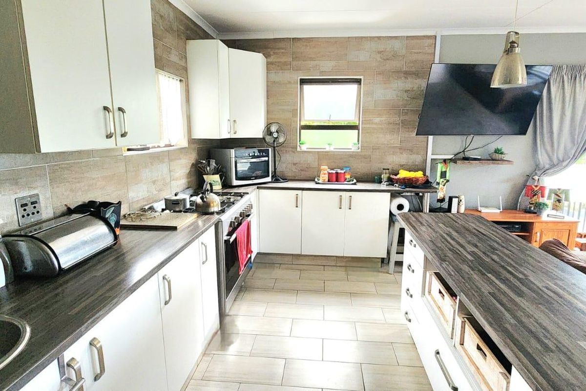 A functional kitchen featuring white cabinetry, dark laminate countertops, a kitchen island, and tiled finishes, offering a practical layout for daily cooking and dining.