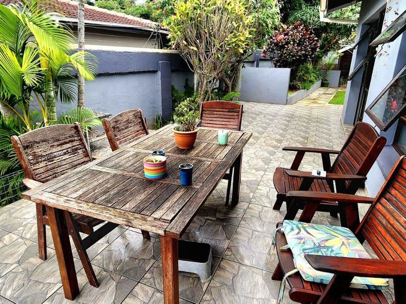 A paved outdoor patio area featuring a boundary wall and access to the home through awning windows.
