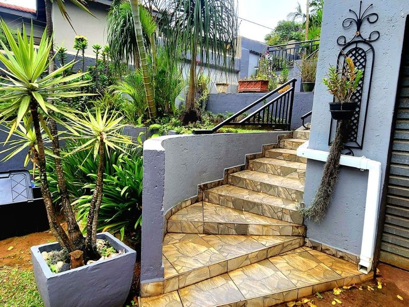 Exterior view of a property featuring a tiled staircase leading to an entrance, adjacent to a garage and a landscaped garden area.