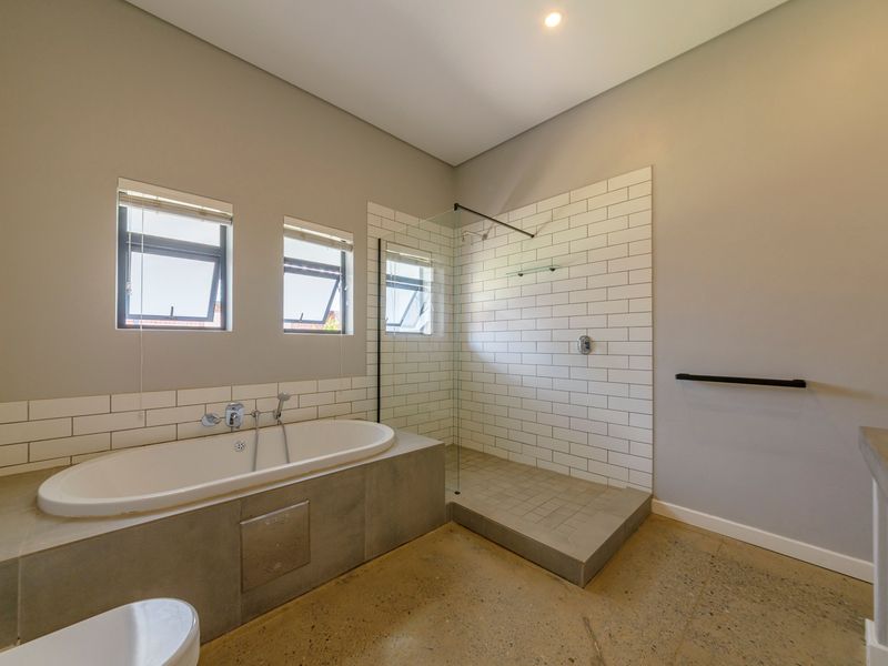 Modern bathroom featuring a built-in bathtub, walk-in shower with subway tile surround, and polished concrete flooring.
