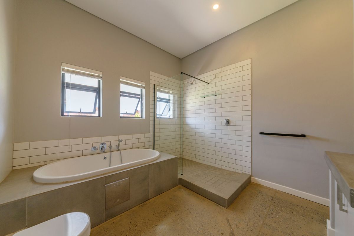 Modern bathroom featuring a built-in bathtub, walk-in shower with subway tile surround, and polished concrete flooring.