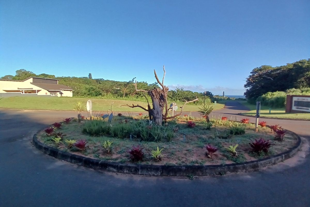 A view of the landscaped roundabout at the entrance of the residential estate, featuring established garden beds and paved access roads.