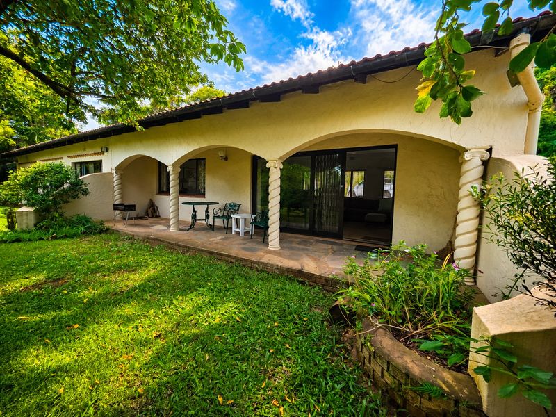 A covered patio area featuring stone flooring, decorative arched columns, and direct access to the interior through sliding glass doors.