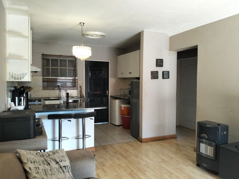 Open plan kitchen and living area featuring granite countertops, built-in cabinetry, and a mix of tiled and laminate flooring.