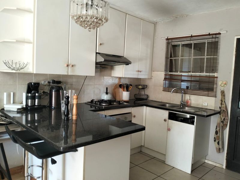 A functional kitchen featuring granite countertops, a gas hob with extractor, and built-in cabinetry, offering a practical layout for daily meal preparation.