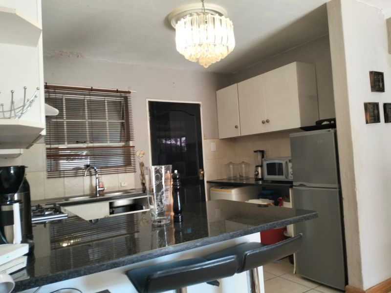 Compact kitchen featuring granite countertops, built-in cabinetry, and a gas hob, with a breakfast bar area.
